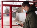 Guy in a medical mask stands at a bus stop. isolated to avoid viral disease covid-19 measles flu chickenpox cold