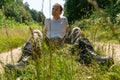 A guy in a military uniform is sitting on the ground against the background of a dirt road. A young handsome guy in a white T- Royalty Free Stock Photo