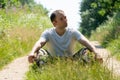 A guy in a military uniform is sitting on the ground against the background of a dirt road. A young handsome guy in a white T- Royalty Free Stock Photo
