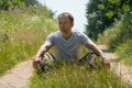 A guy in a military uniform is sitting on the ground against the background of a dirt road. A young handsome guy in a white T- Royalty Free Stock Photo