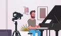 Guy musical blogger recording video on camera man playing classical piano music blog concept modern apartment interior Royalty Free Stock Photo