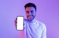 Guy in neon shows smartphone with blank screen
