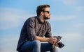 Guy outdoors blue sky background. Vintage equipment. Reporter taking photo. Hipster photographer. Blogger shooting vlog