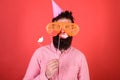 Guy in party hat celebrate, posing with photo props. Emotional diversity concept. Man with beard on cheerful face holds Royalty Free Stock Photo