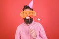 Guy in party hat celebrate, posing with photo props. Emotional diversity concept. Man with beard on cheerful face holds Royalty Free Stock Photo