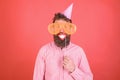 Guy in party hat celebrates, posing with photo props. Hipster in giant sunglasses celebrating. Man with beard on