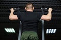 The guy performs a pull-up exercise on the simulator