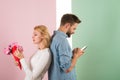 Guy with phone and girl with bouquet flowers, pastel background. Cheating concept. Man hold smartphone texting lover