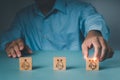 A guy picks a face grin emoticon with his finger to put on a wood block. A survey, poll, or questionnaire based on user experience Royalty Free Stock Photo