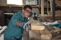 Man in plaid shirt, goggles and gloves checks the quality of the planed board in the workshop, manual labor, home craftsman