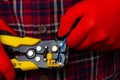 A guy in a plaid shirt and red work gloves is stripping electrical wires with yellow pliers. Royalty Free Stock Photo