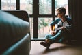 Guy plaing on guitar sits on the floor at home