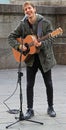 Guy is playing acoustic guitar outside in Milan