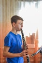 The guy plays the clarinet, looks at the music and plays music in a music school