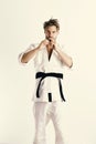 Guy poses in white kimono with black belt. Japanese karate