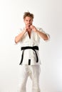Guy poses in white kimono with black belt. Japanese karate