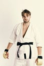 Guy poses in white kimono wearing golden boxing gloves Royalty Free Stock Photo