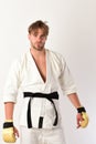 Guy poses in white kimono wearing golden boxing gloves Royalty Free Stock Photo