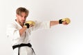 Guy poses in white kimono wearing golden boxing gloves Royalty Free Stock Photo