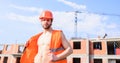 Guy protective helmet stand in front of building made out of red bricks. Builder orange vest helmet work construction