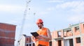 Guy in protective helmet stand in front of building made out of red bricks. Man orange vest and helmet works at Royalty Free Stock Photo