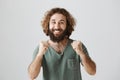 Guy is proud of brother. Portrait of grinning excited easter man with beard and curly hair clenching fists near chest