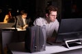 Guy realising amount of work in office at night, sitting at desk working on computer