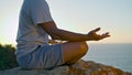 Guy relaxing lotus position in evening ocean sunlight. Unknown yogi meditating