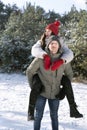 Guy rolls girl on his back. Loving young couple is having fun in winter outdoors Royalty Free Stock Photo