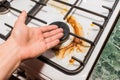 Guy`s hand points to a dirty gas stove burner after home cooking in the kitchen Royalty Free Stock Photo