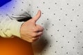 The guy's hand shows the class with a thumbs up on the background of polka dots, the pattern is white and black Royalty Free Stock Photo