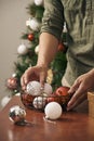 Guy`s hands ornamenting the pine tree with a white ball decoration. Royalty Free Stock Photo