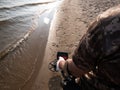 Guy on a sandy coast looking for treasure with a metal detector on a sunny summer day Royalty Free Stock Photo