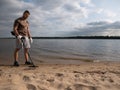 Guy on a sandy coast looking for treasure with a metal detector on a sunny summer day Royalty Free Stock Photo