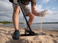 Guy on a sandy coast looking for treasure with a metal detector on a sunny summer day Royalty Free Stock Photo