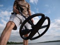 Guy on a sandy coast looking for treasure with a metal detector on a sunny summer day Royalty Free Stock Photo