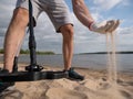 Guy on a sandy coast looking for treasure with a metal detector on a sunny summer day Royalty Free Stock Photo