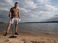 Guy on a sandy coast looking for treasure with a metal detector on a sunny summer day Royalty Free Stock Photo