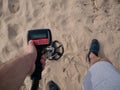 Guy on a sandy ground with a metal detector looking for treasure on a sunny summer day Royalty Free Stock Photo