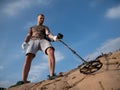 Guy on a sandy ground with a metal detector looking for treasure on a sunny summer day Royalty Free Stock Photo