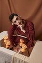 guy in a shirt sits at a table in front of a mirror and cut oranges fabric background Royalty Free Stock Photo