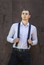 The guy in the shirt and suspenders. The guy stands on a background of wood,