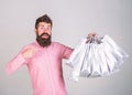 Guy shopping and pointing at bags. Recommendation concept. Hipster on surprised face recommends to buy. Man with beard Royalty Free Stock Photo