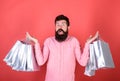 Guy shopping on sales season with discounts. Man with beard and mustache holds shopping bags, red background. Hipster on