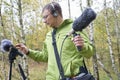 The guy with Shotgun Condenser Microphone and headphones is recording the sounds of nature.
