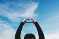 A Guy showing Heart Hand sign on Summer Bluet Sky background