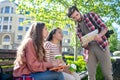 Guy showing map to two girls sitting on bench Royalty Free Stock Photo