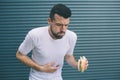 Guy is sick. He is holding burger in hand and looking down. Man is going to vomit. Isolated on striped and blue