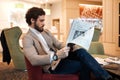 Guy sitting on the sofa, holding newspaper in hands Royalty Free Stock Photo