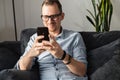 A guy with a smartphone sits on the couch Royalty Free Stock Photo